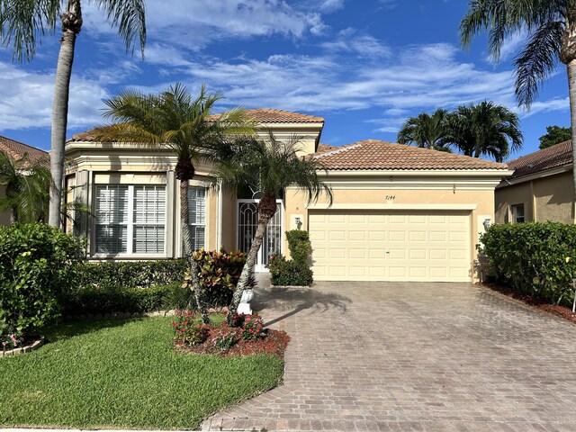 mediterranean / spanish-style house featuring a garage and a front yard