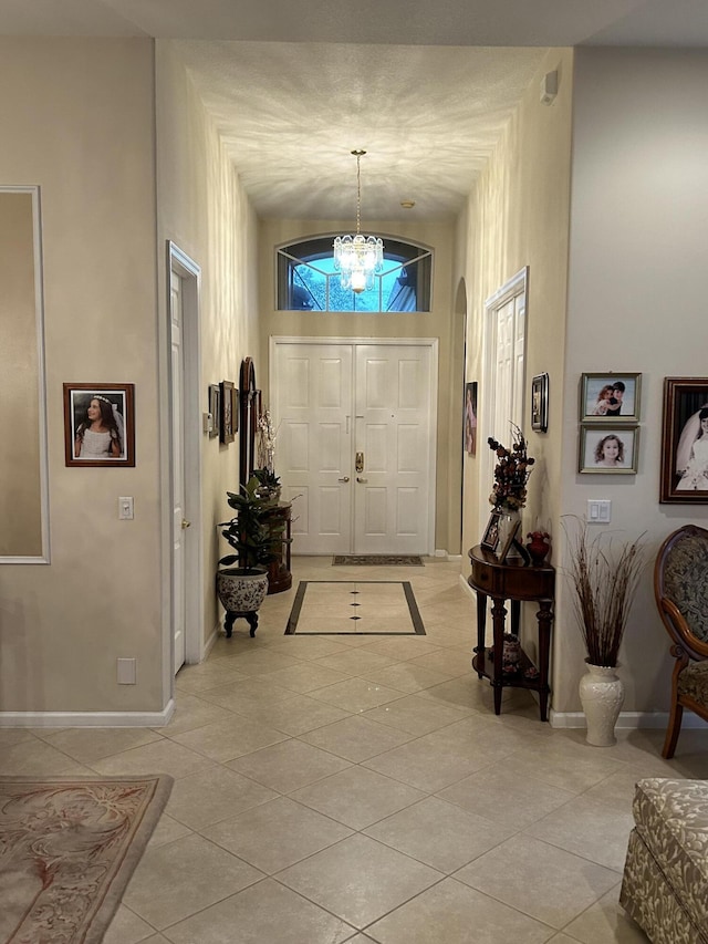 foyer entrance featuring light tile patterned floors, baseboards, and an inviting chandelier