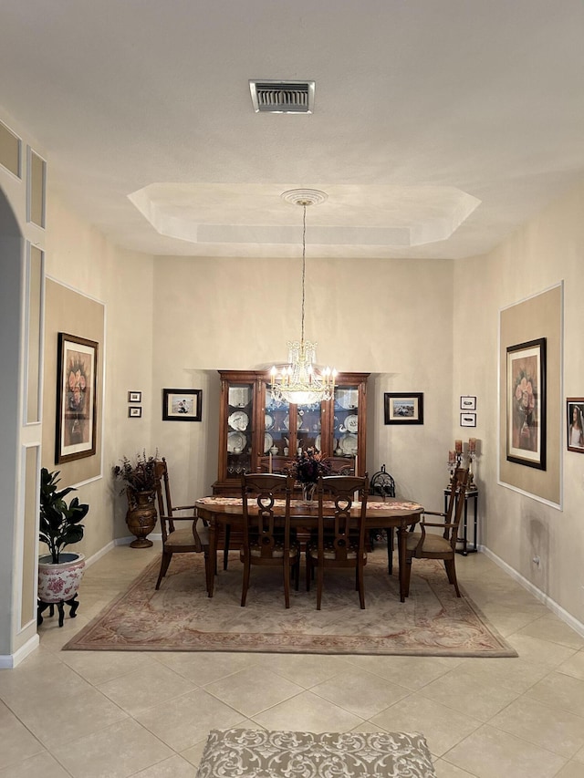 dining area with a notable chandelier, a raised ceiling, visible vents, light tile patterned flooring, and baseboards