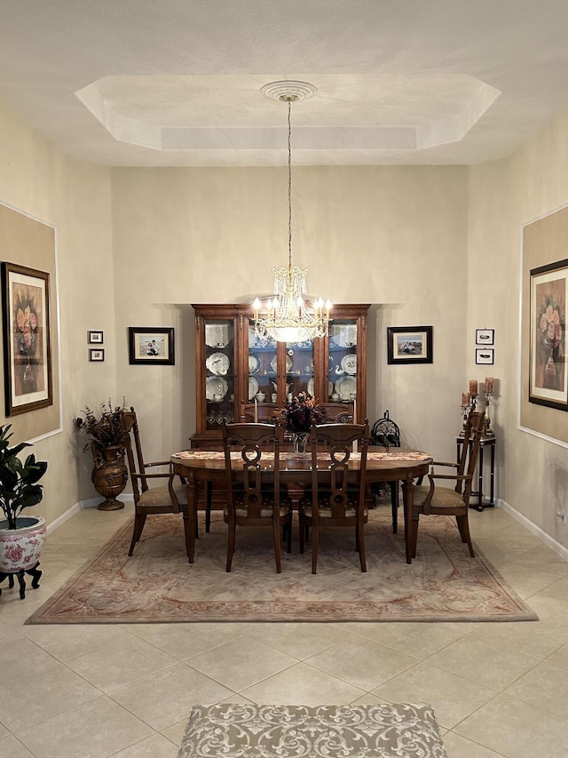 dining area featuring a raised ceiling, baseboards, an inviting chandelier, and light tile patterned floors