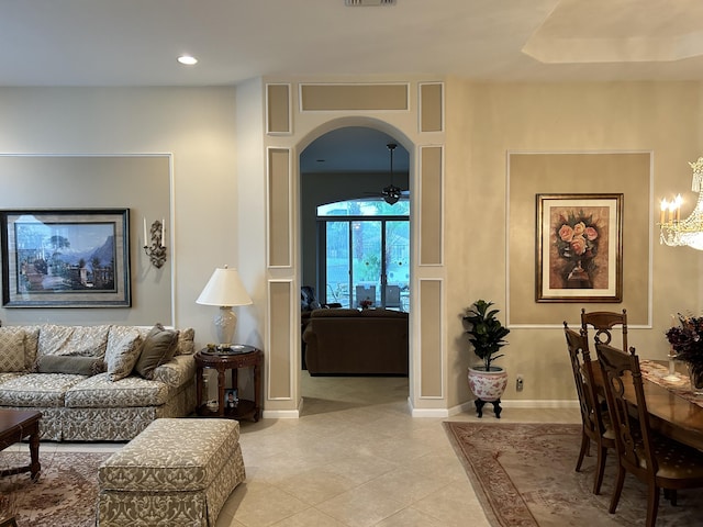 interior space featuring arched walkways, light tile patterned floors, a ceiling fan, and baseboards