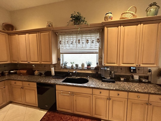 kitchen featuring black dishwasher, dark stone counters, a sink, and decorative backsplash