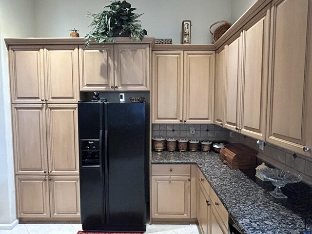 kitchen with black fridge, dark stone counters, tasteful backsplash, and light tile floors