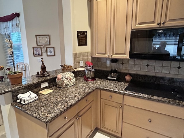 kitchen with dark stone counters, a peninsula, black appliances, and decorative backsplash