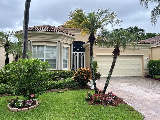 mediterranean / spanish-style home featuring a garage and a front yard