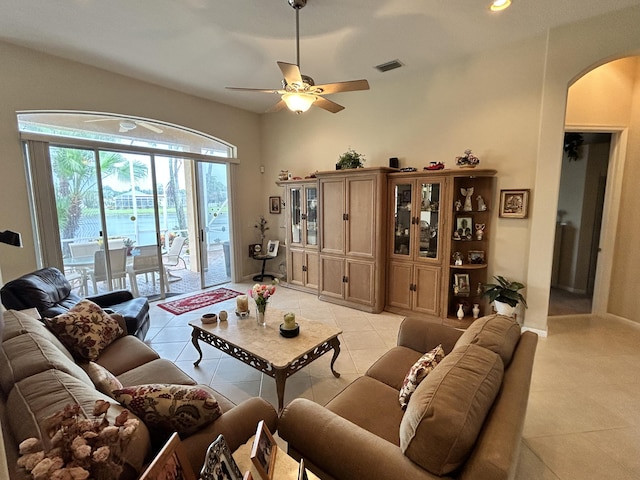 living area with arched walkways, ceiling fan, light tile patterned flooring, and visible vents