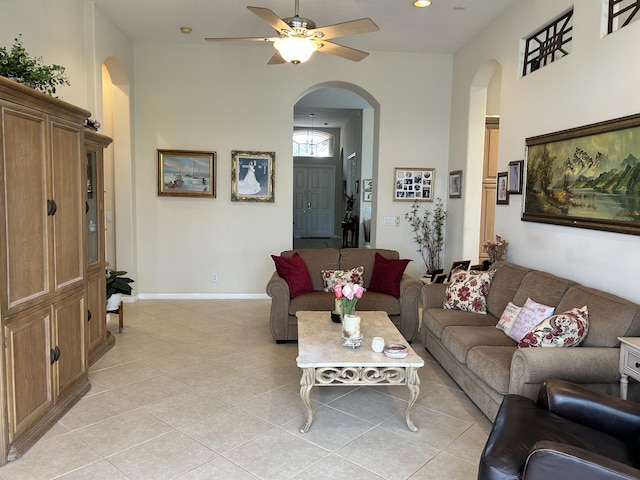 living room featuring light tile patterned floors, baseboards, arched walkways, and a ceiling fan