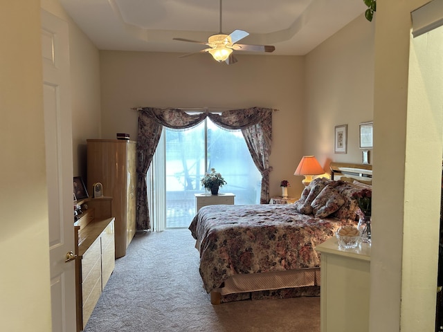 carpeted bedroom featuring ceiling fan, access to outside, and a raised ceiling