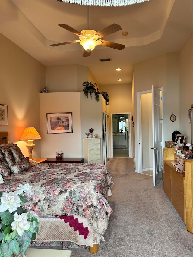 carpeted bedroom featuring ceiling fan and a tray ceiling