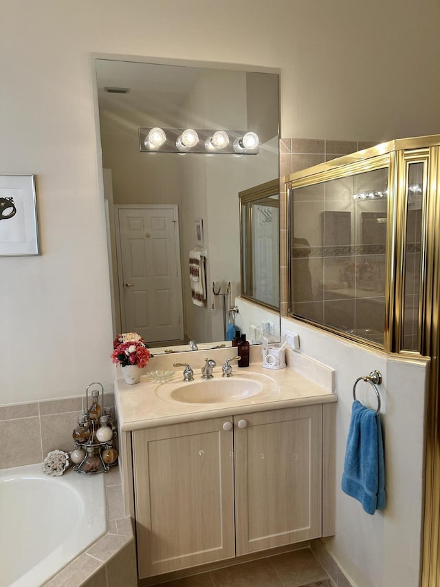 full bath featuring a stall shower, tile patterned floors, vanity, and a bath