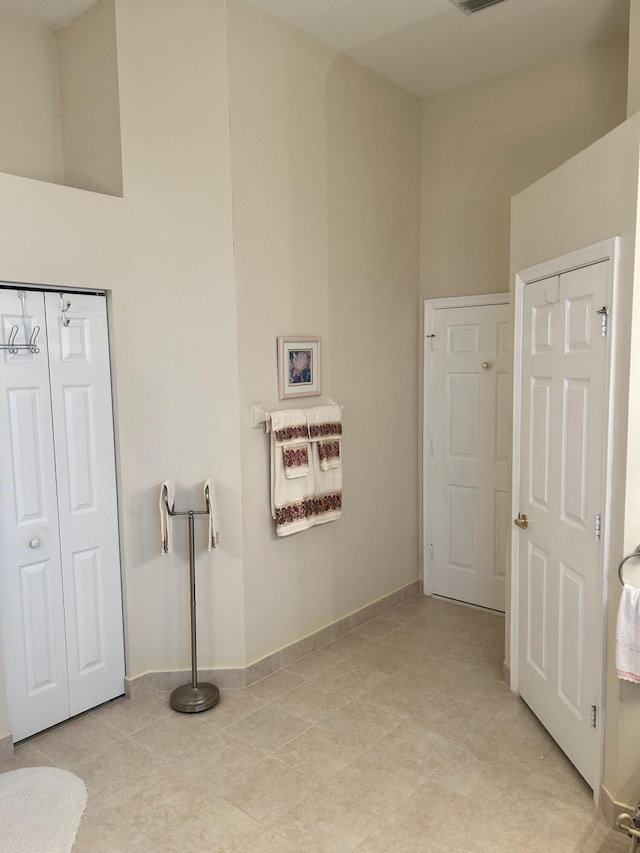 bathroom featuring visible vents, a towering ceiling, and baseboards
