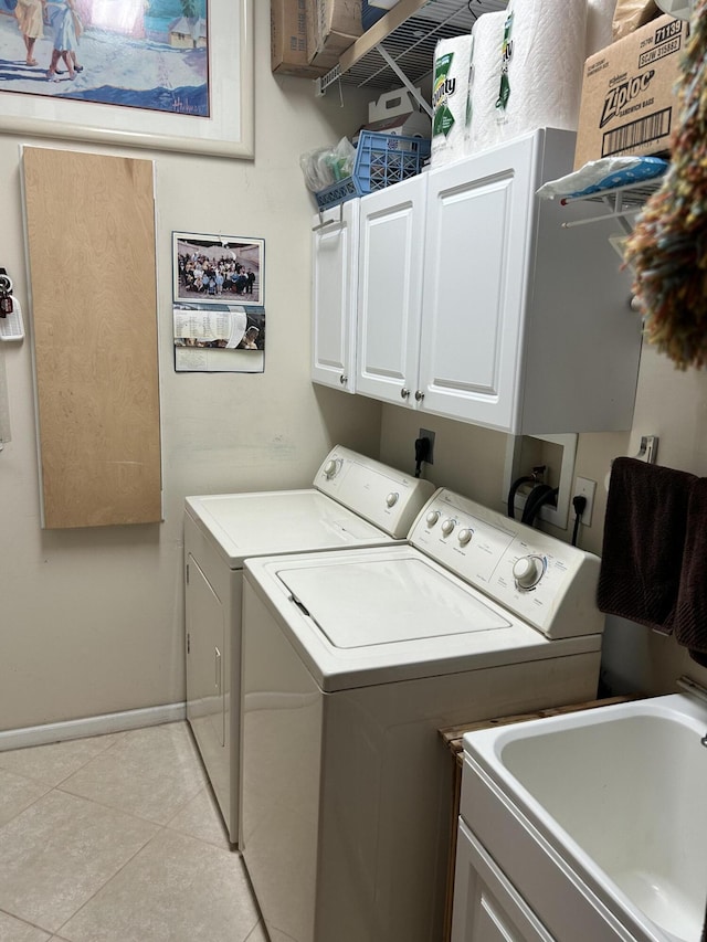 laundry room featuring cabinet space, light tile patterned floors, baseboards, washer and clothes dryer, and a sink