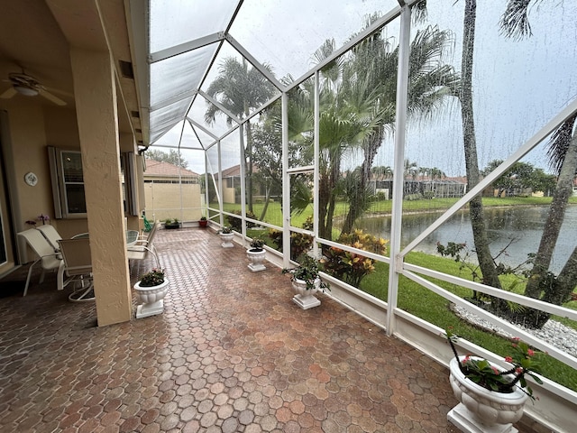 unfurnished sunroom featuring ceiling fan and a water view