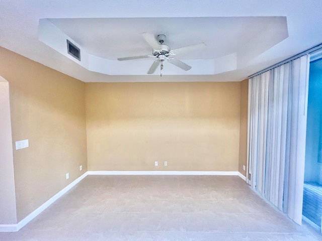 empty room featuring tile patterned flooring, a raised ceiling, and ceiling fan