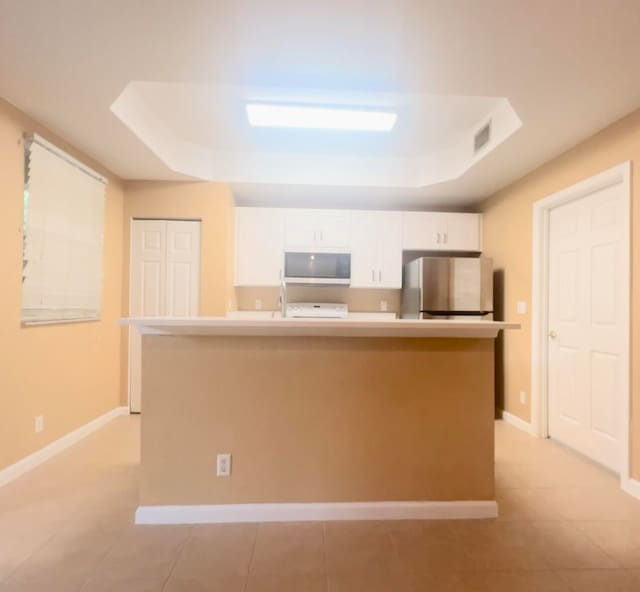 kitchen with white cabinets, refrigerator, and a kitchen island with sink