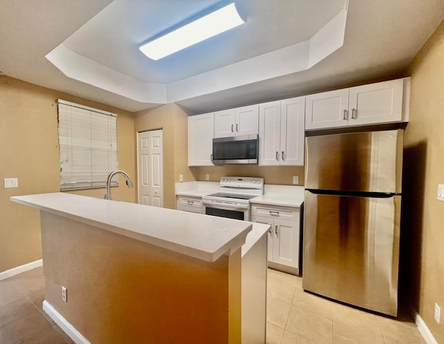 kitchen featuring white cabinets, light tile patterned flooring, appliances with stainless steel finishes, and a tray ceiling