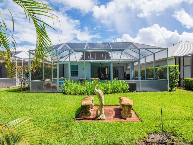 rear view of property featuring ceiling fan, a lanai, and a yard