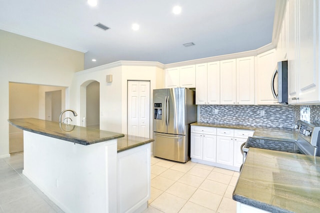 kitchen featuring appliances with stainless steel finishes, tasteful backsplash, white cabinets, and light tile patterned flooring