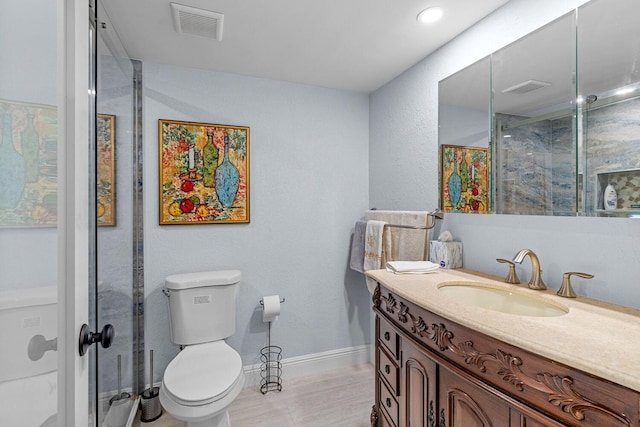 bathroom with hardwood / wood-style floors, a shower with shower door, vanity, and toilet