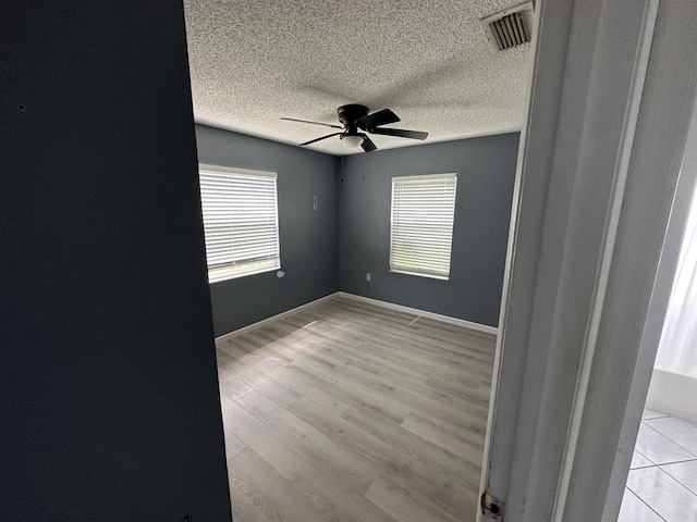 spare room with ceiling fan, light hardwood / wood-style floors, and a textured ceiling