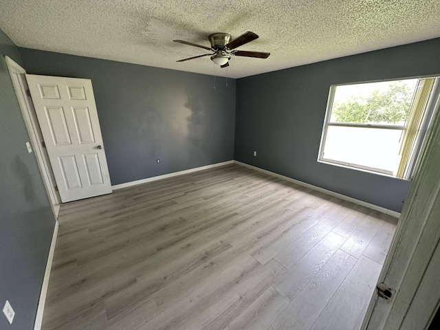 spare room with ceiling fan, light hardwood / wood-style floors, and a textured ceiling