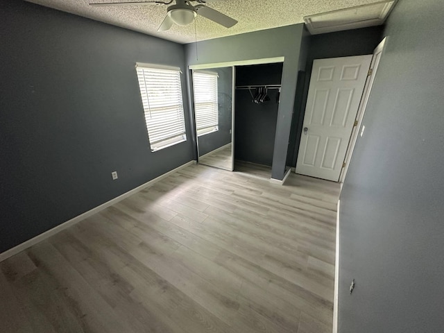 unfurnished bedroom with a textured ceiling, a closet, light hardwood / wood-style flooring, and ceiling fan