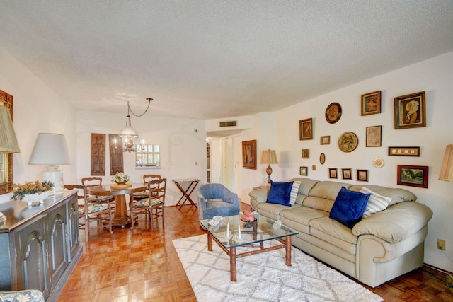 living room featuring parquet floors, a chandelier, and a textured ceiling