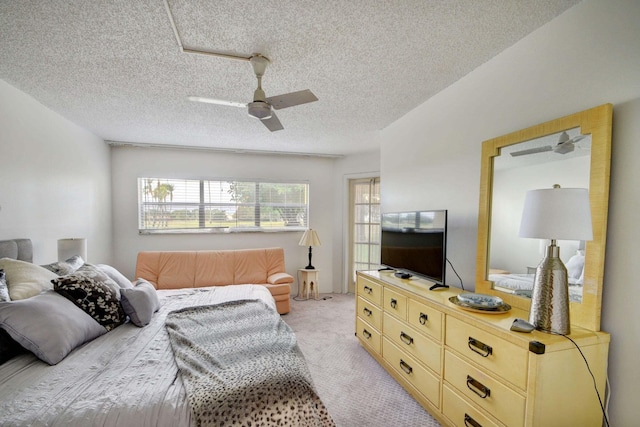 bedroom with ceiling fan, light colored carpet, and a textured ceiling