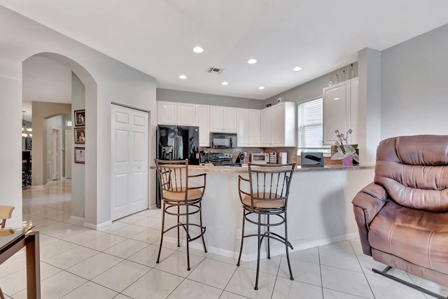 kitchen featuring black appliances, white cabinets, light tile patterned floors, kitchen peninsula, and a breakfast bar area