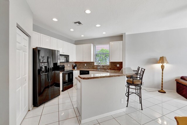 kitchen featuring sink, white cabinets, black appliances, and light tile patterned floors