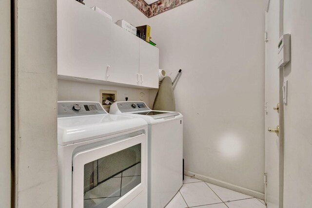 laundry area featuring separate washer and dryer, light tile patterned floors, and cabinets