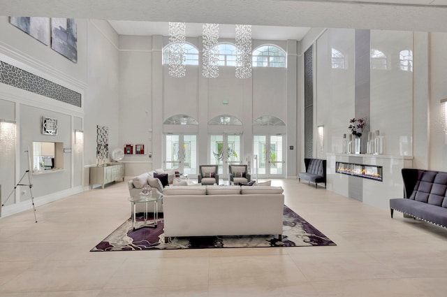 living room featuring a chandelier, a high ceiling, light tile patterned floors, and a healthy amount of sunlight