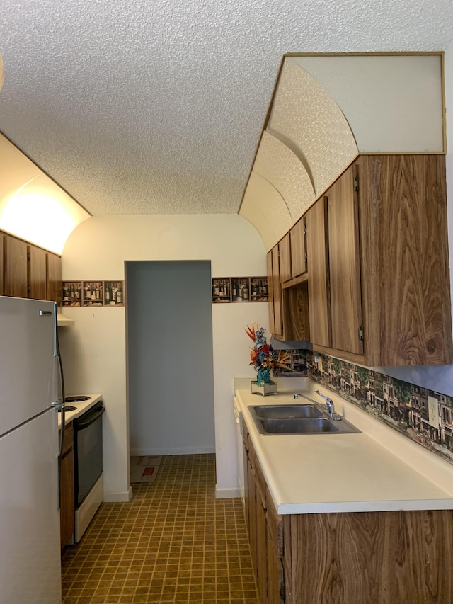 kitchen with white range with electric cooktop, a textured ceiling, fridge, and sink