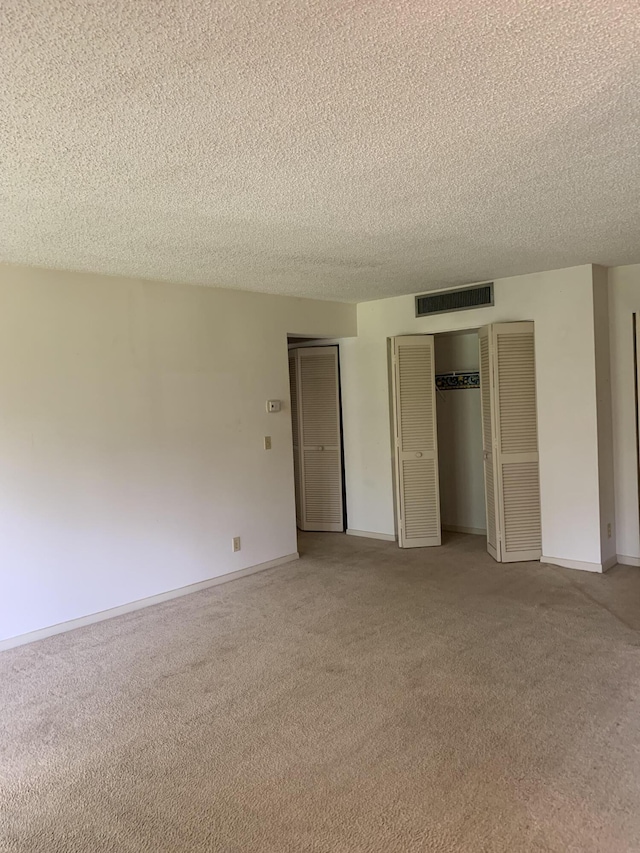 unfurnished bedroom featuring a textured ceiling and carpet