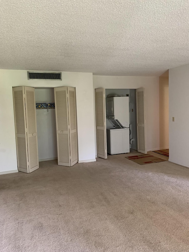 unfurnished bedroom featuring a textured ceiling, multiple closets, and light carpet