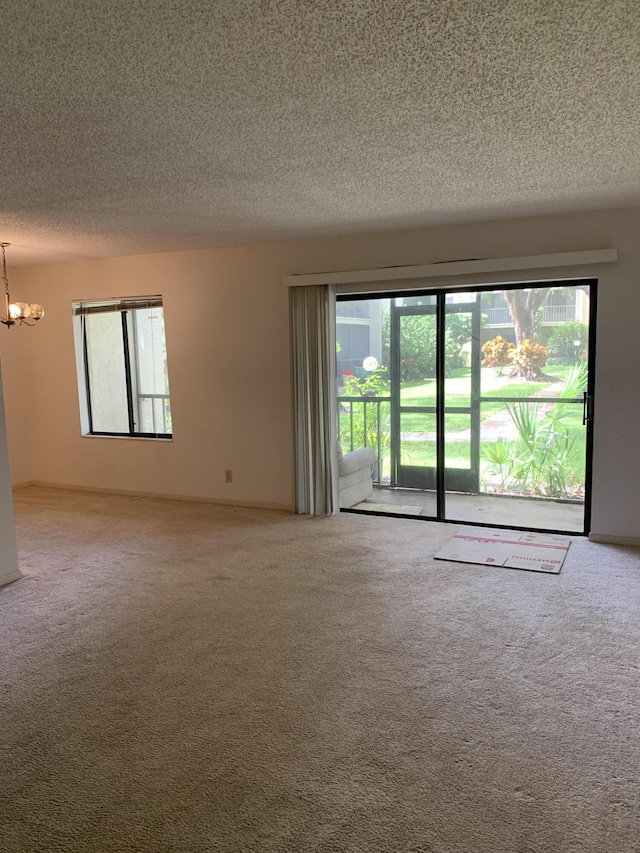 unfurnished room with a textured ceiling, a chandelier, and carpet flooring