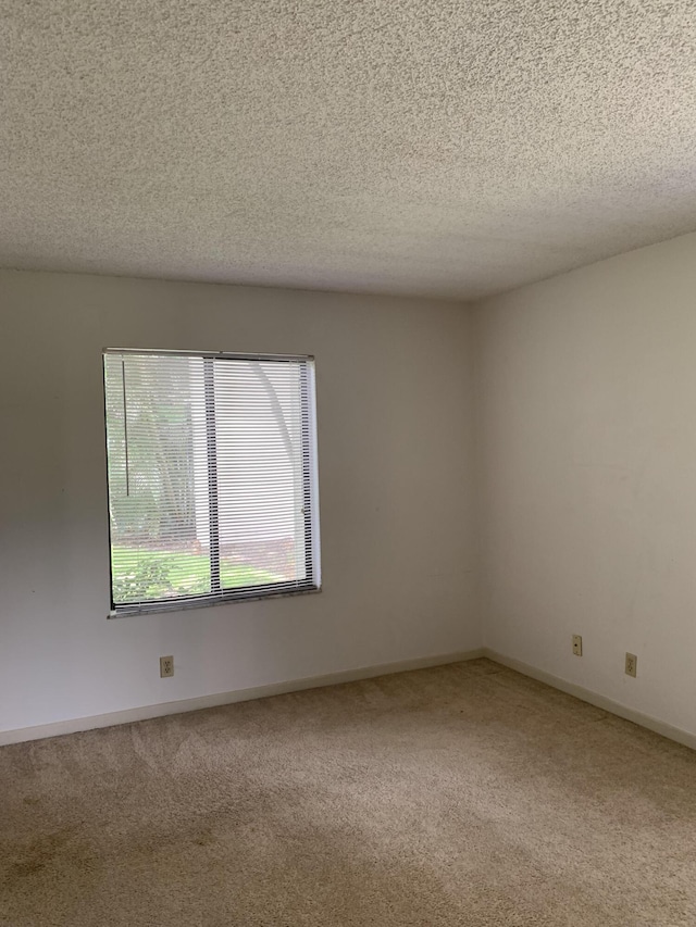 carpeted empty room featuring a textured ceiling