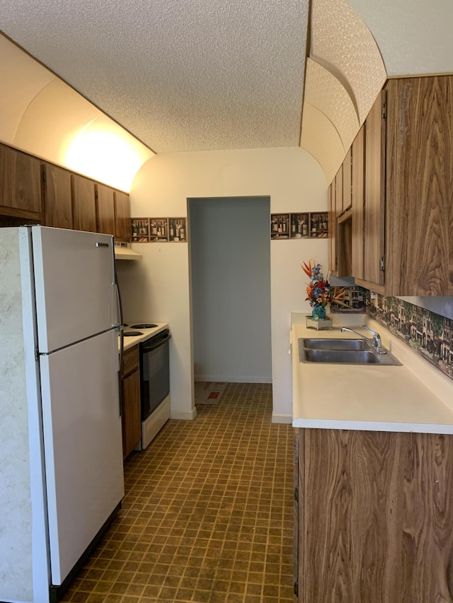 kitchen featuring white refrigerator, range with electric stovetop, a textured ceiling, and sink