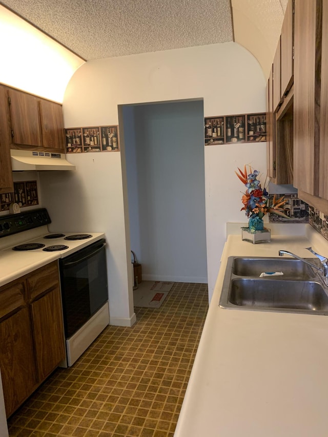 kitchen featuring electric range oven, a textured ceiling, and sink