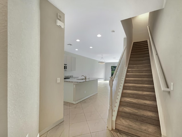 stairway featuring tile patterned flooring and sink