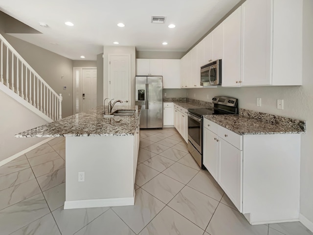 kitchen featuring sink, an island with sink, stone countertops, white cabinets, and appliances with stainless steel finishes