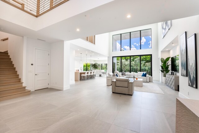 living room with a towering ceiling and light tile patterned flooring