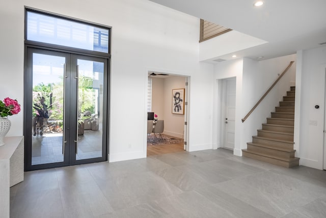 doorway to outside featuring a healthy amount of sunlight, a high ceiling, ceiling fan, and french doors