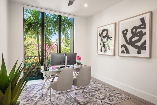 home office featuring light wood-type flooring, expansive windows, and ceiling fan