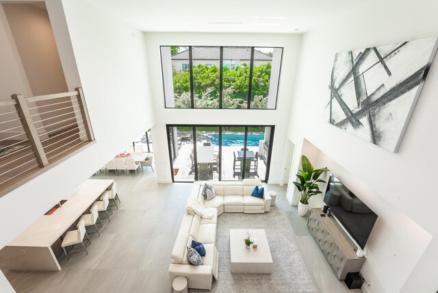 living room with a towering ceiling and light tile patterned floors