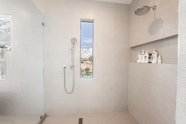 bathroom with a tile shower, a healthy amount of sunlight, and tile patterned flooring