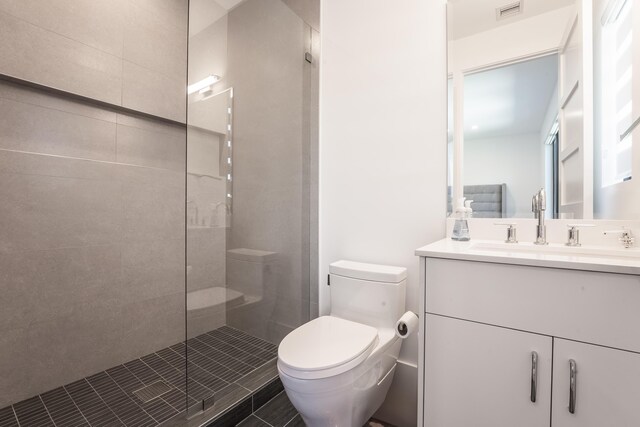 bathroom featuring tile patterned flooring, vanity, toilet, and a tile shower