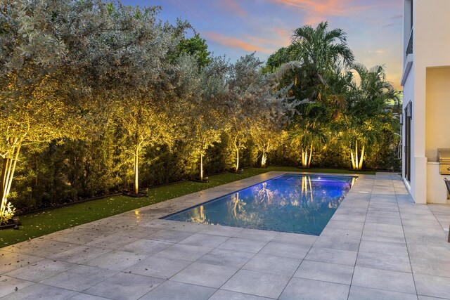 pool at dusk featuring a patio