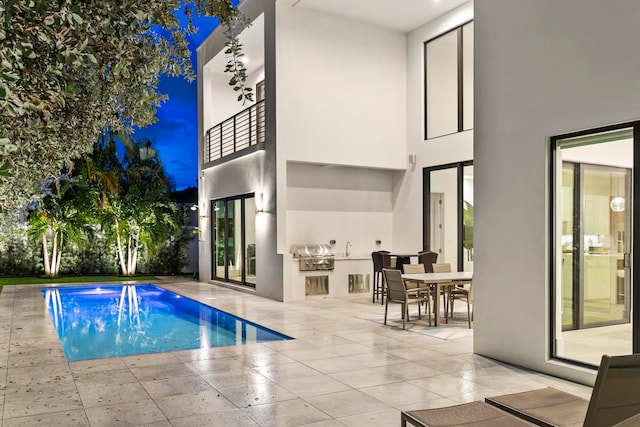 pool at twilight with a grill and a patio area