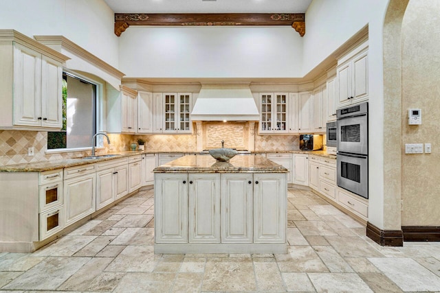 kitchen featuring beamed ceiling, custom range hood, a center island, and sink